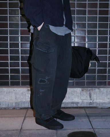 ミリタリートラウザーズを現代的にリファイン。斜めのカーゴポケットが実用的なアクセントを添え、洗練されたテーパードラインが際立ちます。素材には肌馴染みの良い10sヘリンボンを採用。環境に配慮した特殊エイジング・サンフェード加工と随所のリメイクにより、リアリティのある褪色感とヴィンテージな佇まいを表現しました。

Modernized military trousers with a refined tapered fit and slanted cargo pockets. Crafted from soft 10s herringbone, this BLACKA pair features special sun-fading and remake details. It achieves an authentic, time-worn vintage character while utilizing eco-conscious processing to minimize environmental impact.