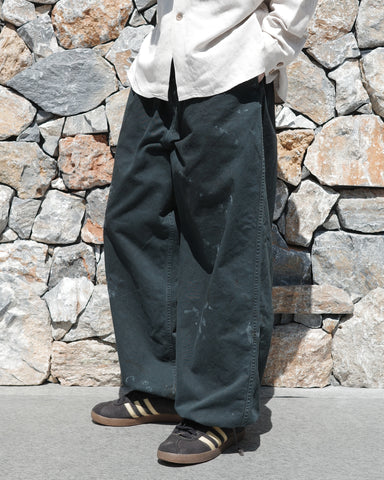 フロントに2タックを施し、ワタリから裾にかけてゆとりを持たせたワイルドなワイドシルエット。裾のドローコードでシルエットの変化も自在に楽しめます。素材には耐久性に優れ、綾織特有の柔らかさを持つ厚手チノクロスを採用。ストーンバイオウォッシュと汚し加工を重ねることで、長年穿き込んだようなリアルな質感と深みのある表情を引き出しました。

Wild, wide-silhouette pants with double-tucked fronts and adjustable hem drawcords. Crafted from durable, soft chino cloth, this CHARCOAL pair features a stone bio-wash and staining process. This creates an authentic, rugged texture and a deeply weathered look, blending vintage workwear aesthetics with a modern, voluminous fit.