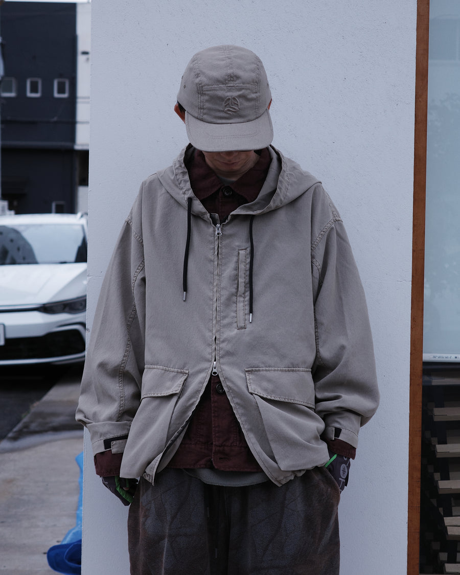 ポリエステル100％でありながら、綿のような質感と軽量性を備えた高機能な一着。タスラン加工糸を使用したポリエステルオックスを採用し、シワになりにくく速乾性に優れたイージーケア性を実現しました。本来染色が困難な素材に特殊顔料染めを施すことで、化繊特有の光沢を抑えた、ナチュラルで奥行きのある絶妙なフェード感を表現しています。

A high-performance piece crafted from polyester oxford, offering a cotton-like touch with lightweight, quick-dry, and wrinkle-resistant properties. This GRAY BEIGE item features a special pigment dye—a rare process for polyester—achieving a sophisticated, faded texture and a matte finish that defies its synthetic origins.