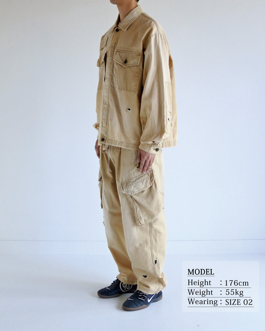 ミリタリーのシャツジャケットを現代的シルエットに更新。裾のドローコードでスタイルに合わせた変化を楽しめます。素材には肌馴染みの良い10sヘリンボンを採用。環境に配慮した特殊エイジング・サンフェード加工とダメージ加工を施すことで、クラシカルな生地にリアリティのある褪色感とヴィンテージライクな佇まいを表現しました。

A modern military shirt jacket with hem drawcords for an adjustable silhouette. Crafted from soft 10s herringbone, this KHAKI piece undergoes a special sun-fade and damage process. It achieves a realistic, time-worn vintage look with authentic distressing while minimizing environmental impact through eco-conscious processing.