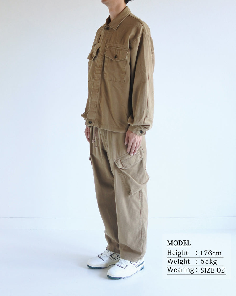ミリタリーのシャツジャケットを現代的シルエットに更新。裾のドローコードで着丈のニュアンスを自在に調整可能です。素材には、やや甘織りで肌馴染みの良い10sヘリンボンを採用。ストーンバイオウォッシュを施すことで、クラシカルな生地感に柔らかな風合いとこなれ感をプラスした、着回し力の高い一着に仕上げました。

A modern update to the classic military shirt jacket, featuring hem drawcords for an adjustable silhouette. Crafted from 10s herringbone, slightly loose-knitted for a soft, comfortable touch. This KHAKI piece has been treated with a stone bio-wash, giving the traditional weave a natural, worn-in texture and a sophisticated casual feel.