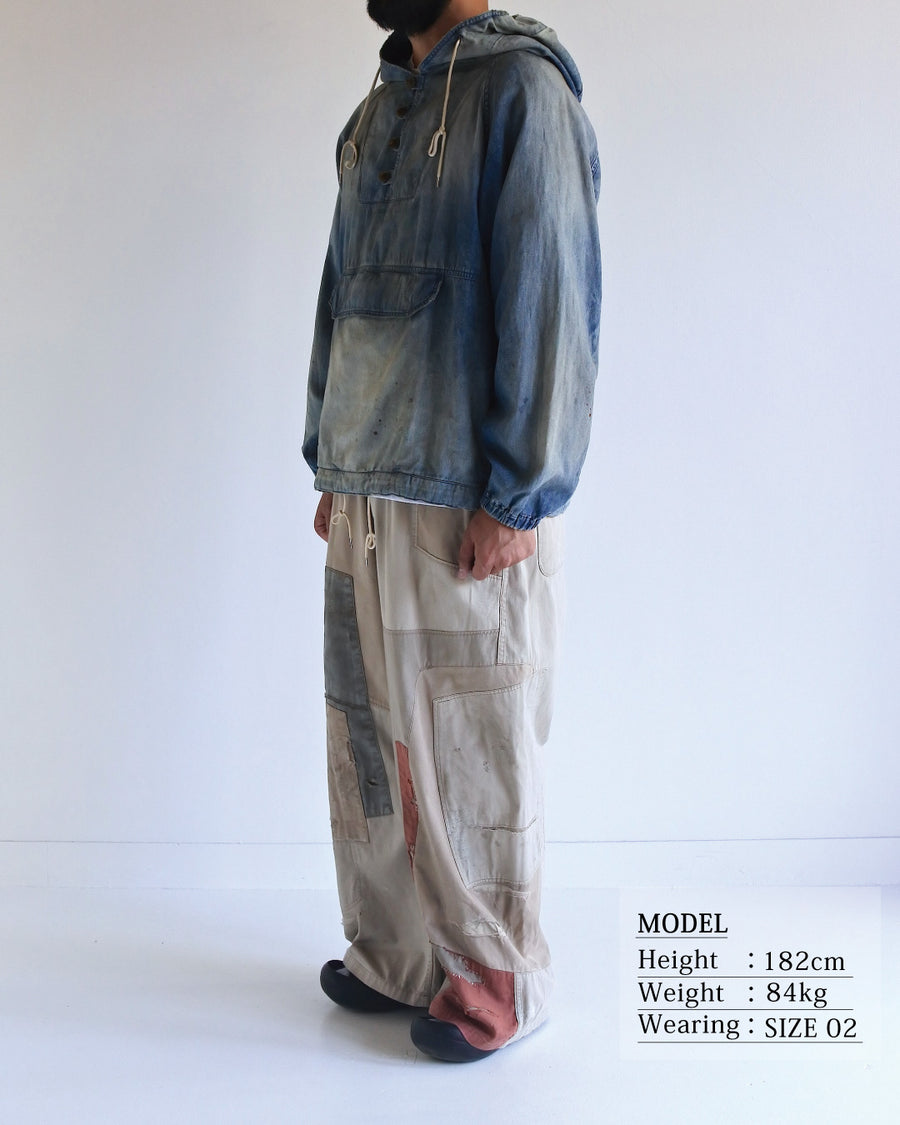 フード口のボタンの開閉により、首まわりのニュアンスを変えて楽しめる一着。素材には、経糸にコットンムラ糸、緯糸に綿麻混紡糸を使用した綿麻6ozデニムを採用しました。シャープなムラ感とリネン混ならではの粗野な風合いが、ヴィンテージの魅力を引き立てます。エイジング加工を施すことで、全体にリアリティのあるアタリ感を出し、長年着込んだような深みのある表情に仕上げました。A versatile piece featuring adjustable hood buttons to create a clean or relaxed neckline. Crafted from 6oz cotton-linen denim, the fabric combines sharp slub textures with a rustic linen feel for an authentic vintage character. Treated with an aging process to create realistic wear and fade, this INDIGO garment offers a sophisti