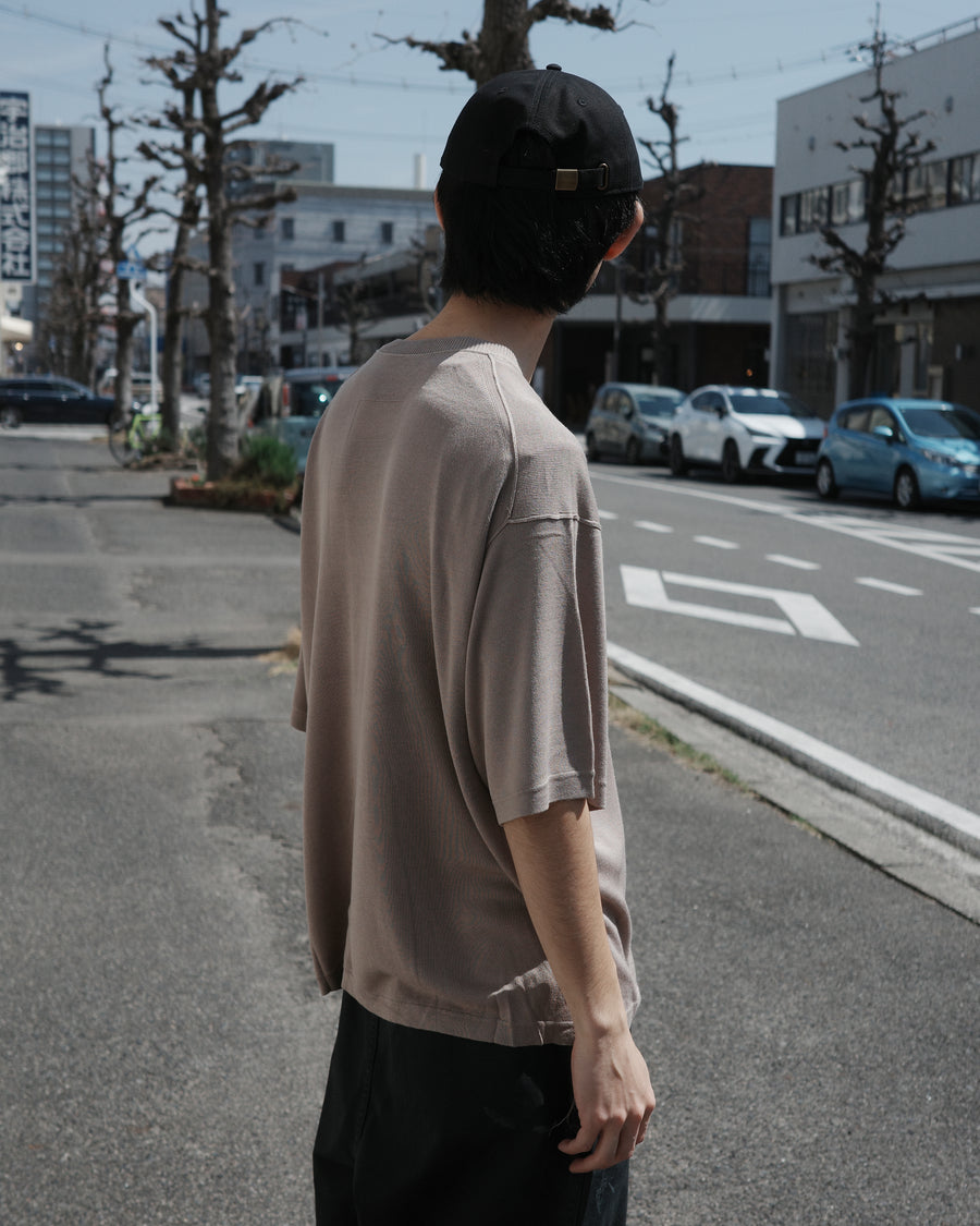 ディテールを極限まで削ぎ落とし、着心地とシルエットを追求したニットTシャツ。気候変化に対応する新たなアプローチとして、軽量で吸水・放湿性に優れた竹（バンブー）素材を採用しました。滑らかでとろみのある肌触りと、袖を通した瞬間に感じる清涼感は格別です。家庭洗濯も可能で、日常に圧倒的な心地よさを提供します。

A minimalist knit T-shirt focused entirely on fit and comfort. Crafted from bamboo yarn, this lightweight, durable material offers exceptional moisture absorption and a refreshing cool-to-the-touch feel. This LIGHT BEIGE piece features a silky, fluid drape that provides overwhelming comfort, perfect for changing climates, and is conveniently home-washable.