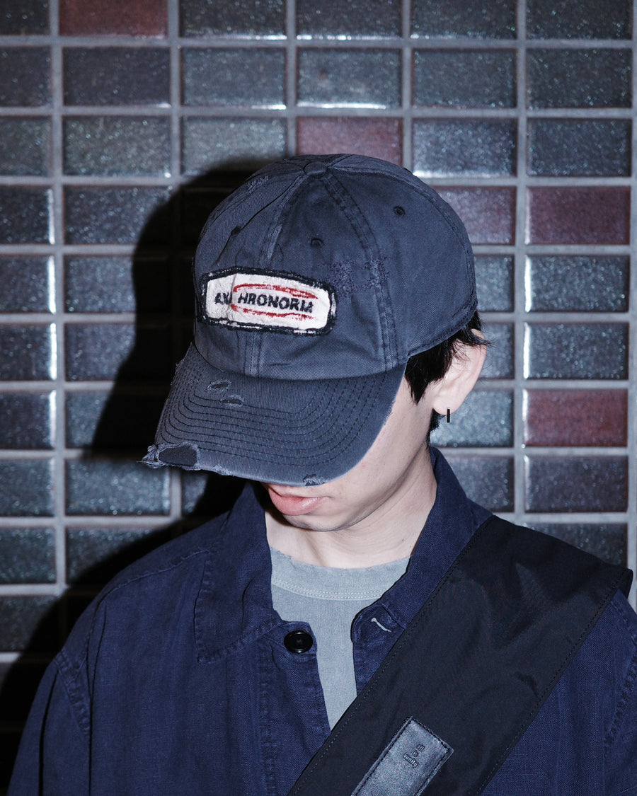 ダメージ加工とステッチ補強で、長年使い込まれた風合いを表現したキャップ。オリジナルワッペンにも同様の加工を施し、全体の統一感を高めました。素材には先染めのピグメントコットンキャンバスを採用。実用性とヴィンテージな佇まいを兼ね備え、スタイリングにこなれたアクセントを添える一着に仕上げています。

A distressed cap featuring reinforced stitching for a rugged, time-worn look. Both the body and the original patch are meticulously aged for a cohesive vintage aesthetic. Crafted from pre-dyed pigment cotton canvas, this BLACK piece combines durability with a sophisticated, lived-in feel, perfect for adding character to any outfit.