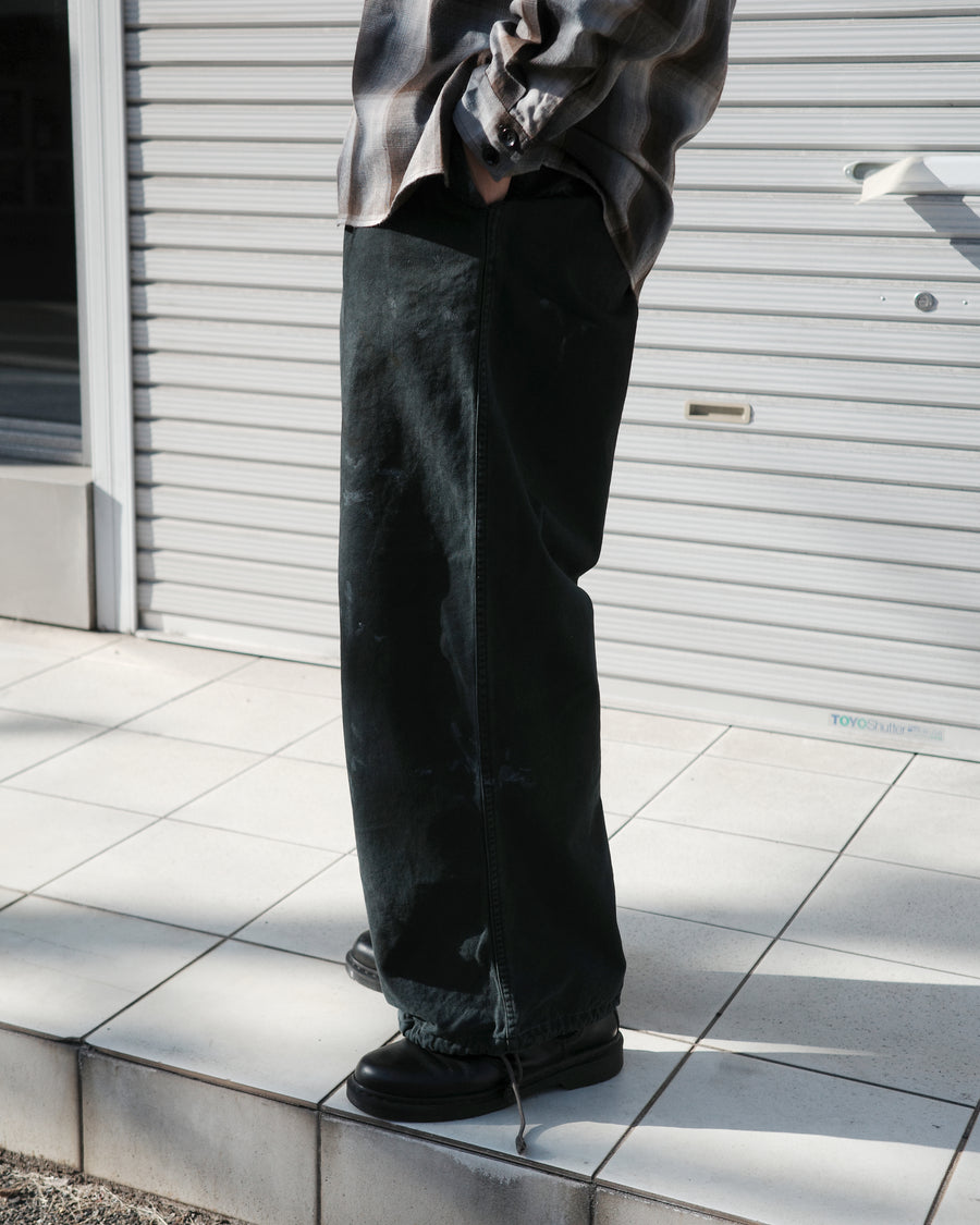 フロントに2タックを施し、ワタリから裾にかけてゆとりを持たせたワイルドなワイドシルエット。裾のドローコードでシルエットの変化も自在に楽しめます。素材には耐久性に優れ、綾織特有の柔らかさを持つ厚手チノクロスを採用。ストーンバイオウォッシュと汚し加工を重ねることで、長年穿き込んだようなリアルな質感と深みのある表情を引き出しました。

Wild, wide-silhouette pants with double-tucked fronts and adjustable hem drawcords. Crafted from durable, soft chino cloth, this CHARCOAL pair features a stone bio-wash and staining process. This creates an authentic, rugged texture and a deeply weathered look, blending vintage workwear aesthetics with a modern, voluminous fit.