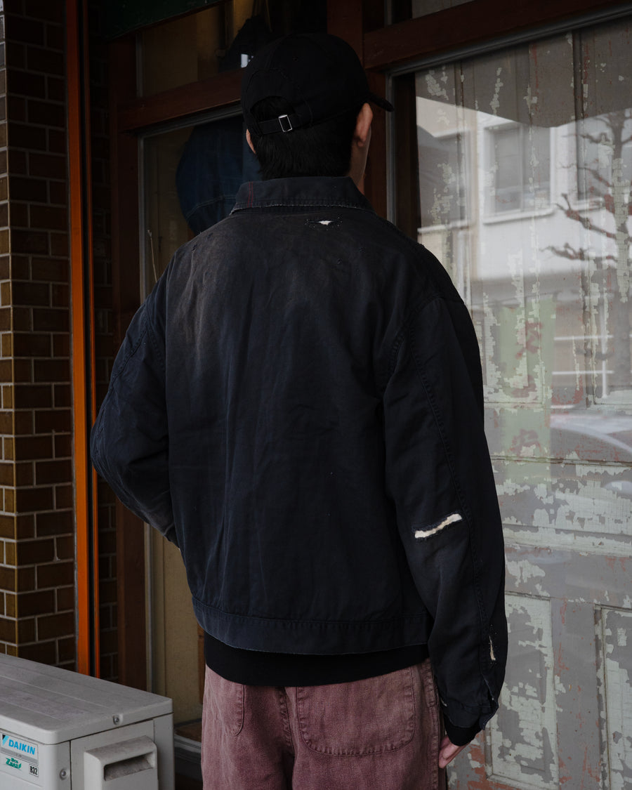ヴィンテージのワークジャケットを現代的シルエットで再現。柔らかくコシのある20番手ツイルに、環境負荷を抑えた特殊エイジング・サンフェード加工、さらにダメージ加工を施すことで、長年着込んだようなリアルな色落ちと風合いを忠実に表現しました。裏地には高密度なコットンスレーキを採用。鮮やかなブラックのボディに、オリジナルワッペンがアクセントを添える、ヴィンテージ感溢れる一着です。
A modern reimagining of the classic vintage work jacket. Made from soft 20s twill and treated with a special sun-fade and damage process for a realistic, time-worn look. This BLACK jacket features high-density lining and original custom patches, creating a unique, heritage-inspired finish with authentic distressing.