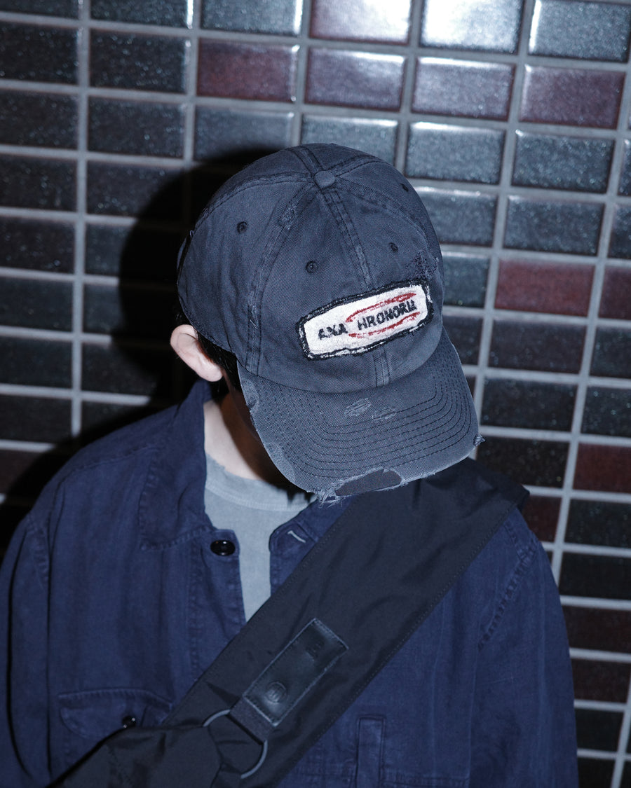 ダメージ加工とステッチ補強で、長年使い込まれた風合いを表現したキャップ。オリジナルワッペンにも同様の加工を施し、全体の統一感を高めました。素材には先染めのピグメントコットンキャンバスを採用。実用性とヴィンテージな佇まいを兼ね備え、スタイリングにこなれたアクセントを添える一着に仕上げています。

A distressed cap featuring reinforced stitching for a rugged, time-worn look. Both the body and the original patch are meticulously aged for a cohesive vintage aesthetic. Crafted from pre-dyed pigment cotton canvas, this BLACK piece combines durability with a sophisticated, lived-in feel, perfect for adding character to any outfit.