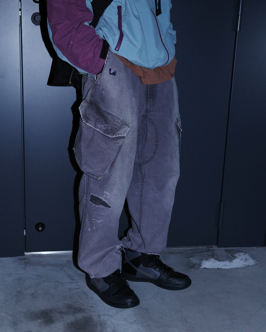 ミリタリートラウザーズを現代的にリファイン。斜めのカーゴポケットが実用的なアクセントを添え、洗練されたテーパードラインが際立ちます。素材には肌馴染みの良い10sヘリンボンを採用。環境に配慮した特殊エイジング・サンフェード加工と随所のリメイクにより、リアリティのある褪色感とヴィンテージな佇まいを表現しました。

Modernized military trousers with a refined tapered fit and slanted cargo pockets. Crafted from soft 10s herringbone, this CHARCPAL pair features special sun-fading and remake details. It achieves an authentic, time-worn vintage character while utilizing eco-conscious processing to minimize environmental impact.