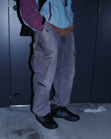 ミリタリートラウザーズを現代的にリファイン。斜めのカーゴポケットが実用的なアクセントを添え、洗練されたテーパードラインが際立ちます。素材には肌馴染みの良い10sヘリンボンを採用。環境に配慮した特殊エイジング・サンフェード加工と随所のリメイクにより、リアリティのある褪色感とヴィンテージな佇まいを表現しました。

Modernized military trousers with a refined tapered fit and slanted cargo pockets. Crafted from soft 10s herringbone, this CHARCPAL pair features special sun-fading and remake details. It achieves an authentic, time-worn vintage character while utilizing eco-conscious processing to minimize environmental impact.