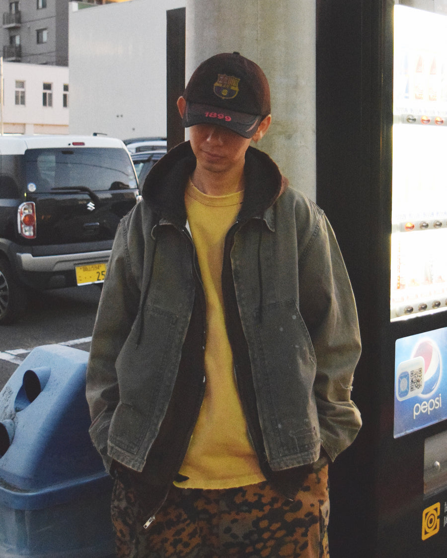 【 商品名：リメイクデトロイトダックジャケット 】

本製品は、ゆとりのある身幅とややクロップド丈に設計されたブラックカラーのジャケットで、インナーアイテムとのレイヤードを楽しめるバランスの良いシルエットが特徴です。生地には頒布の中でも最も薄手の11号帆布生地を採用しており、強度・耐久性に優れ、着用を重ねるごとにアタリなどの経年変化を味わえる素材です。さらに、水や薬品の使用量を抑えながら生地の凹凸部分のアタリを強調し、同時に自然な脱色感を生み出す特殊エイジング加工を施し、加えてサンフェードによるダメージ加工を加えることで、より奥行きのある表情に仕上げています。