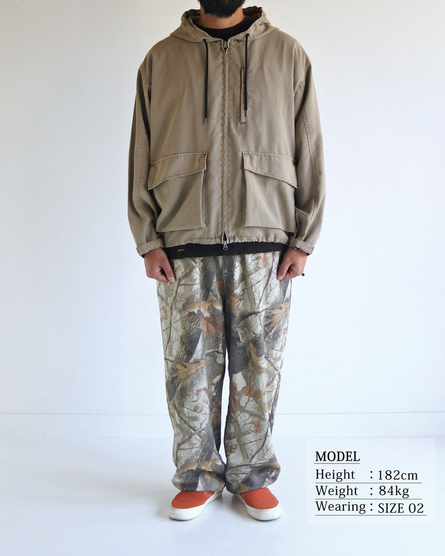 ポリエステル100％でありながら、綿のような質感と軽量性を備えた高機能な一着。タスラン加工糸を使用したポリエステルオックスを採用し、シワになりにくく速乾性に優れたイージーケア性を実現しました。本来染色が困難な素材に特殊顔料染めを施すことで、化繊特有の光沢を抑えた、ナチュラルで奥行きのある絶妙なフェード感を表現しています。

A high-performance piece crafted from polyester oxford, offering a cotton-like touch with lightweight, quick-dry, and wrinkle-resistant properties. This GRAY BEIGE item features a special pigment dye—a rare process for polyester—achieving a sophisticated, faded texture and a matte finish that defies its synthetic origins.