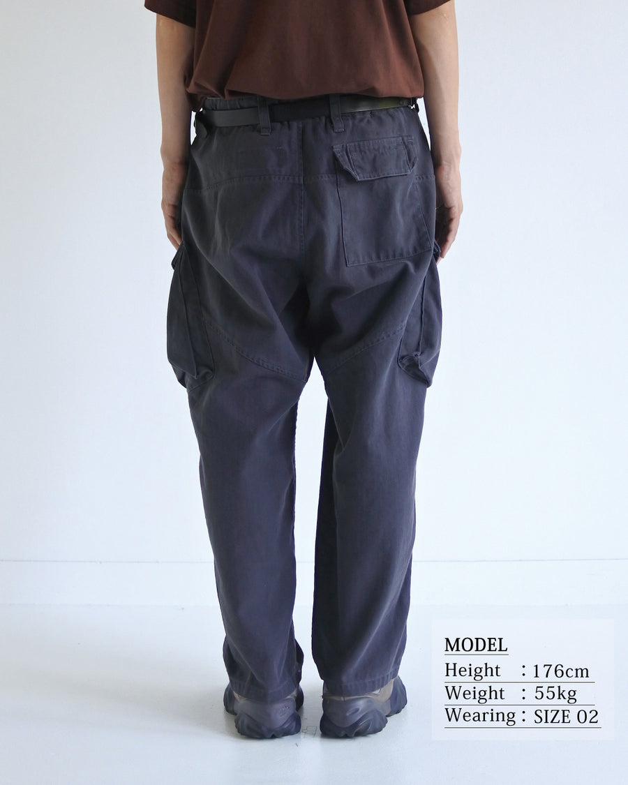 ミリタリートラウザーズをベースに、シルエットを現代的にリファイン。印象的な斜めのカーゴポケットが、立体感と実用性を両立させています。裾にかけて緩やかに絞られたテーパードラインにより、無骨ながらも洗練された印象に。素材には肌馴染みの良い10sヘリンボンを採用し、ストーンバイオウォッシュで柔らかな風合いとこなれ感を引き出しました。

Military trousers refined with a modern tapered silhouette. The distinctive slanted cargo pockets offer both practical utility and a structured look. Crafted from soft, classic 10s herringbone, this CHARCOAL pair has been treated with a stone bio-wash, providing a comfortable, worn-in texture and a sophisticated take on rugged style.