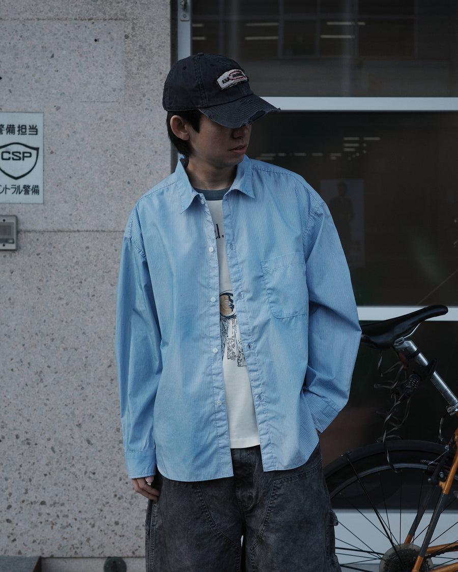 クリーンな高密度ストライプシャツに、スプレーによる顔料吹き付け加工を施し、自然なムラ感を与えた一着。リラックス感のあるシルエットが、上品さとラフさを絶妙なバランスで両立させています。素材には米綿100%の高密度ストライプ生地を採用。綿100%のナチュラルな風合いながら、シワになりにくい実用性も兼ね備えています。

A clean stripe shirt enhanced with a subtle pigment spray process for a natural, textured look. The relaxed silhouette perfectly balances elegance with a casual edge. Crafted from high-density US cotton stripe fabric, this BLUE STRIPE piece offers a crisp feel that is naturally wrinkle-resistant while maintaining the comfort of 100% cotton.