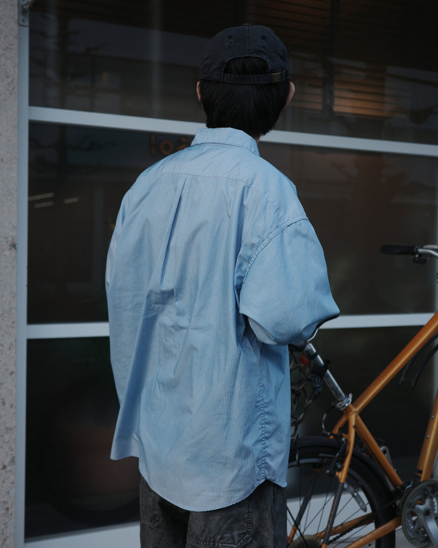 クリーンな高密度ストライプシャツに、スプレーによる顔料吹き付け加工を施し、自然なムラ感を与えた一着。リラックス感のあるシルエットが、上品さとラフさを絶妙なバランスで両立させています。素材には米綿100%の高密度ストライプ生地を採用。綿100%のナチュラルな風合いながら、シワになりにくい実用性も兼ね備えています。

A clean stripe shirt enhanced with a subtle pigment spray process for a natural, textured look. The relaxed silhouette perfectly balances elegance with a casual edge. Crafted from high-density US cotton stripe fabric, this BLUE STRIPE piece offers a crisp feel that is naturally wrinkle-resistant while maintaining the comfort of 100% cotton.