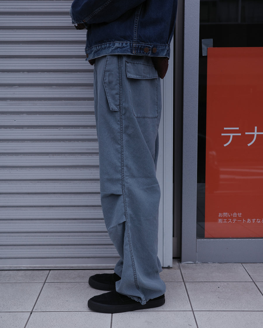 ポリエステル100％ながら、綿のような質感と軽量性を備えた高機能素材を採用。タスラン加工糸によるポリエステルオックスは、シワになりにくく速乾性にも優れています。染色が困難なポリエステルに特殊顔料染めを施すことで、化繊特有の光沢を抑え、ナチュラルで奥行きのある絶妙なフェード感と落ち着いた表情を実現しました。

High-performance polyester oxford with a cotton-like touch, offering quick-dry and wrinkle-resistant benefits. This GRAY BLUE item features a special pigment dye—a rare process for polyester—achieving a sophisticated, faded texture and a matte finish that perfectly balances technical utility with a natural, lived-in aesthetic.