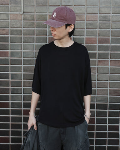 ディテールを極限まで削ぎ落とし、着心地とシルエットを追求したニットTシャツ。気候変化に対応する新たなアプローチとして、軽量で吸水・放湿性に優れた竹（バンブー）素材を採用しました。滑らかでとろみのある肌触りと、袖を通した瞬間に感じる清涼感は格別です。家庭洗濯も可能で、日常に圧倒的な心地よさを提供します。

A minimalist knit T-shirt focused entirely on fit and comfort. Crafted from bamboo yarn, this lightweight, durable material offers exceptional moisture absorption and a refreshing cool-to-the-touch feel. This BLACK piece features a silky, fluid drape that provides overwhelming comfort, perfect for changing climates, and is conveniently home-washable.