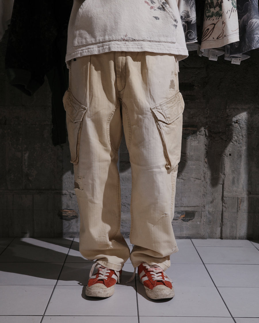 ミリタリートラウザーズを現代的にリファイン。斜めのカーゴポケットが実用的なアクセントを添え、洗練されたテーパードラインが際立ちます。素材には肌馴染みの良い10sヘリンボンを採用。環境に配慮した特殊エイジング・サンフェード加工と随所のリメイクにより、リアリティのある褪色感とヴィンテージな佇まいを表現しました。

Modernized military trousers with a refined tapered fit and slanted cargo pockets. Crafted from soft 10s herringbone, this KHAKI pair features special sun-fading and remake details. It achieves an authentic, time-worn vintage character while utilizing eco-conscious processing to minimize environmental impact.