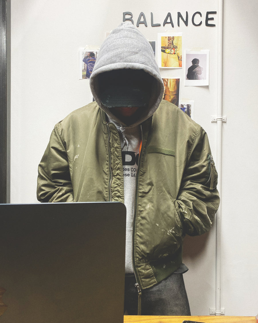 忠実なディテールを保ちながら、シルエットを現代的に整えたMA-1ジャケット。加工によりヴィンテージの風合いを再現した一着です。肉厚でミリタリーらしいツイル生地を使用し、打ち込みの密度や肌触りまでビンテージMA-1に近い仕上がりに。さらに、ダートペイントや特殊吹き付け、ダメージ加工を重ね、洗いをかけて染料を自然に剥がすことで、深みのある表情を生み出しています。カラーはオリーブ。