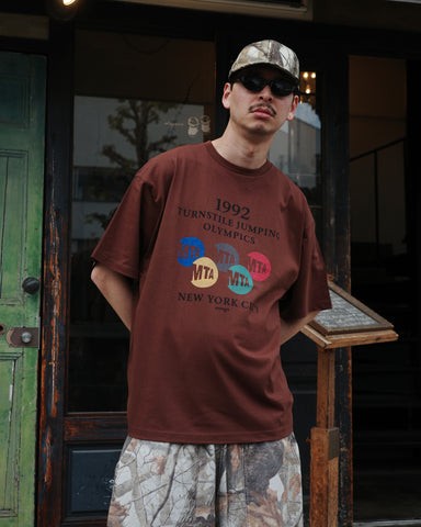 ANACHRONORM × Souvenyr NYC ジャンピング 半袖Tシャツ ブラウン | コラボグラフィック ニューヨーク コットン100%
