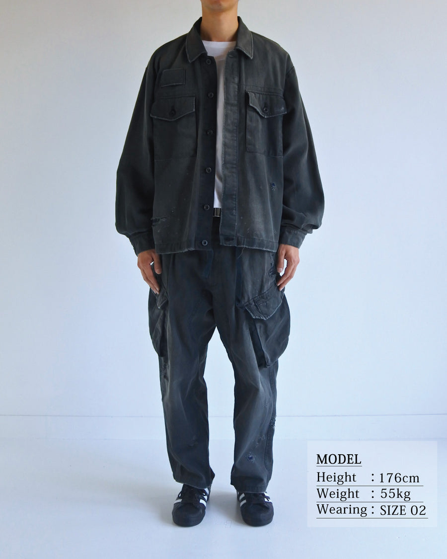 ミリタリーのシャツジャケットを現代的シルエットに更新。裾のドローコードでスタイルに合わせた変化を楽しめます。素材には肌馴染みの良い10sヘリンボンを採用。環境に配慮した特殊エイジング・サンフェード加工とダメージ加工を施すことで、クラシカルな生地にリアリティのある褪色感とヴィンテージライクな佇まいを表現しました。

A modern military shirt jacket with hem drawcords for an adjustable silhouette. Crafted from soft 10s herringbone, this BLACK piece undergoes a special sun-fade and damage process. It achieves a realistic, time-worn vintage look with authentic distressing while minimizing environmental impact through eco-conscious processing.