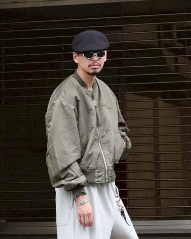 忠実なディテールを保ちながら、シルエットを現代的に整えたMA-1ジャケット。加工によりヴィンテージの風合いを再現した一着です。肉厚でミリタリーらしいツイル生地を使用し、打ち込みの密度や肌触りまでビンテージMA-1に近い仕上がりに。さらに、ダートペイントや特殊吹き付け、ダメージ加工を重ね、洗いをかけて染料を自然に剥がすことで、深みのある表情を生み出しています。カラーはオリーブ。