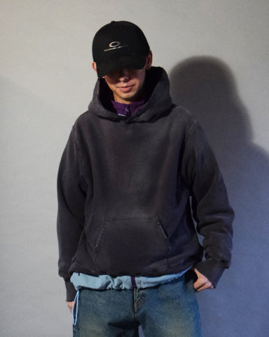 ミニマルなデザインをベースに、ヴィンテージの風合いを追求したリバースウィーブスウェットパーカー。低速で編み立てた30/10裏毛は、ドライなタッチと程よいハリ・コシが特徴です。硫化染め後、水を使用しないサスティナブルブリーチとダメージ加工を施し、長年の着用と日焼けによるリアルな褪色感を環境に配慮しながら表現しました。

An original reverse-weave hoodie crafted from 30/10 French Terry, slowly knitted for a dry, structured touch. This PURPLE hoodie features a waterless sustainable bleach and damage process following a sulfur dye, authentically recreating the sun-faded look of vintage sweats while staying eco-conscious.