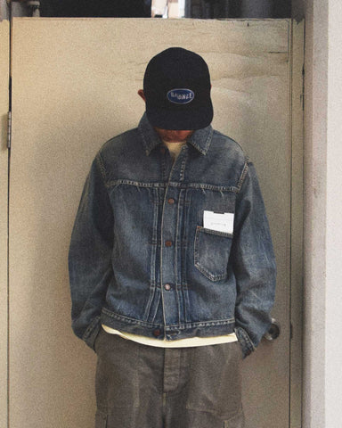 70502XX 1stタイプをベースに、シルエットと細部を現代的に再構築したデニムジャケット。旧式力織機による12.5ozセルビッチデニムを使用しました。5年ほど高頻度で着用した状態を再現した加工により、全体的な色落ちと力強いアタリ感を表現。中濃色のブルーがヴィンテージの風格を漂わせ、長年連れ添ったような愛着を感じさせる一着に仕上げています。

A refined denim jacket based on the 70502XX 1st type, crafted from 12.5oz selvedge denim. The "Five Year" aging finish replicates high-frequency wear, resulting in a faded mid-blue tone and bold, authentic wear patterns. This piece masterfully blends historical design with a rugged, pre-worn character that adds immediate depth to any wa