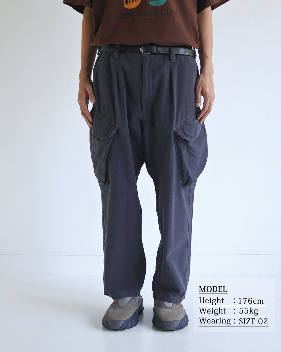 ミリタリートラウザーズをベースに、シルエットを現代的にリファイン。印象的な斜めのカーゴポケットが、立体感と実用性を両立させています。裾にかけて緩やかに絞られたテーパードラインにより、無骨ながらも洗練された印象に。素材には肌馴染みの良い10sヘリンボンを採用し、ストーンバイオウォッシュで柔らかな風合いとこなれ感を引き出しました。

Military trousers refined with a modern tapered silhouette. The distinctive slanted cargo pockets offer both practical utility and a structured look. Crafted from soft, classic 10s herringbone, this CHARCOAL pair has been treated with a stone bio-wash, providing a comfortable, worn-in texture and a sophisticated take on rugged style.