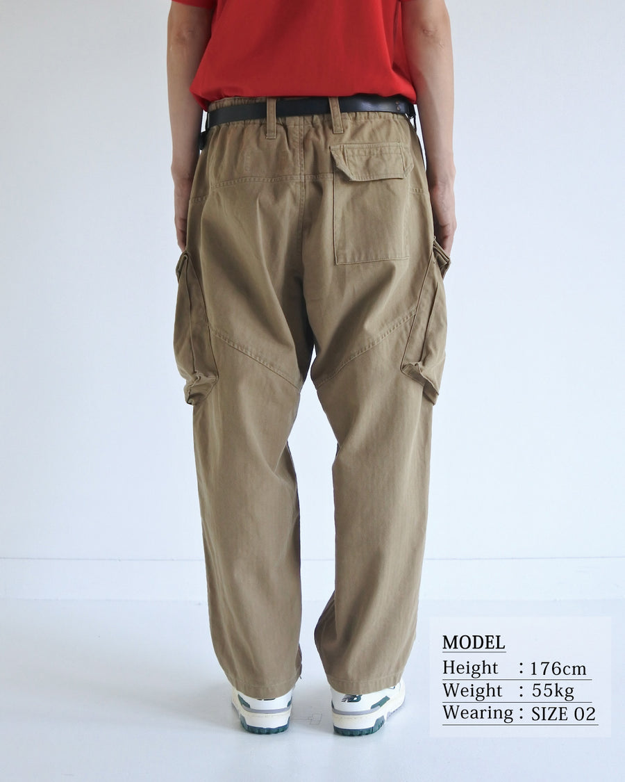 ミリタリートラウザーズをベースに、シルエットを現代的にリファイン。印象的な斜めのカーゴポケットが、立体感と実用性を両立させています。裾にかけて緩やかに絞られたテーパードラインにより、無骨ながらも洗練された印象に。素材には肌馴染みの良い10sヘリンボンを採用し、ストーンバイオウォッシュで柔らかな風合いとこなれ感を引き出しました。

Military trousers refined with a modern tapered silhouette. The distinctive slanted cargo pockets offer both practical utility and a structured look. Crafted from soft, classic 10s herringbone, this KHAKI pair has been treated with a stone bio-wash, providing a comfortable, worn-in texture and a sophisticated take on rugged style.