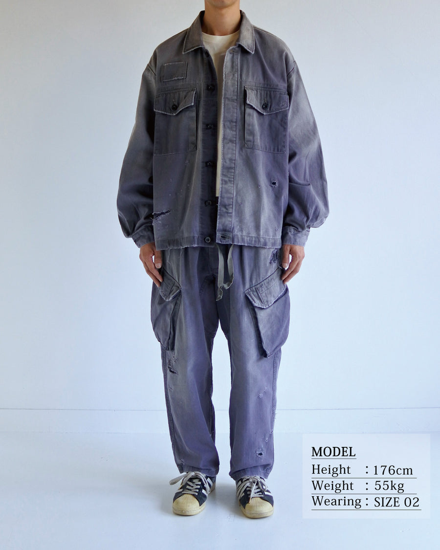 ミリタリーのシャツジャケットを現代的シルエットに更新。裾のドローコードでスタイルに合わせた変化を楽しめます。素材には肌馴染みの良い10sヘリンボンを採用。環境に配慮した特殊エイジング・サンフェード加工とダメージ加工を施すことで、クラシカルな生地にリアリティのある褪色感とヴィンテージライクな佇まいを表現しました。

A modern military shirt jacket with hem drawcords for an adjustable silhouette. Crafted from soft 10s herringbone, this CHARCOAL piece undergoes a special sun-fade and damage process. It achieves a realistic, time-worn vintage look with authentic distressing while minimizing environmental impact through eco-conscious processing.