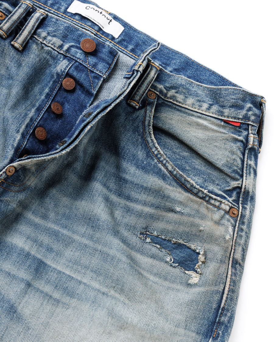 1985年のLEVIS 550をベースに再構築した、ワイドテーパードのリメイク5Pデニム。
12.5ozデニムのタテ糸には中白のインディゴロープ染色糸を使用し、ムラ感のある豊かな表情を演出。タテ落ちとインディゴの濃淡を活かすことで、ヴィンテージにはない独自の風合いを表現しています。さらに手作業のトーンコントロールと特別なエイジング加工を加えることで奥行きある仕上がりに。オリジナル染料の吹き付けにより、モダンでソリッドな印象も併せ持つ一本です。This remade 5P denim features a wide tapered silhouette inspired by the 1985 LEVIS 550.
The 12.5oz denim uses medium-white indigo rope–dyed warp yarns, giving it a textured, slubby character.
By highlighting vertical fading and vivid indigo variations, it achieves a look distinct from vin