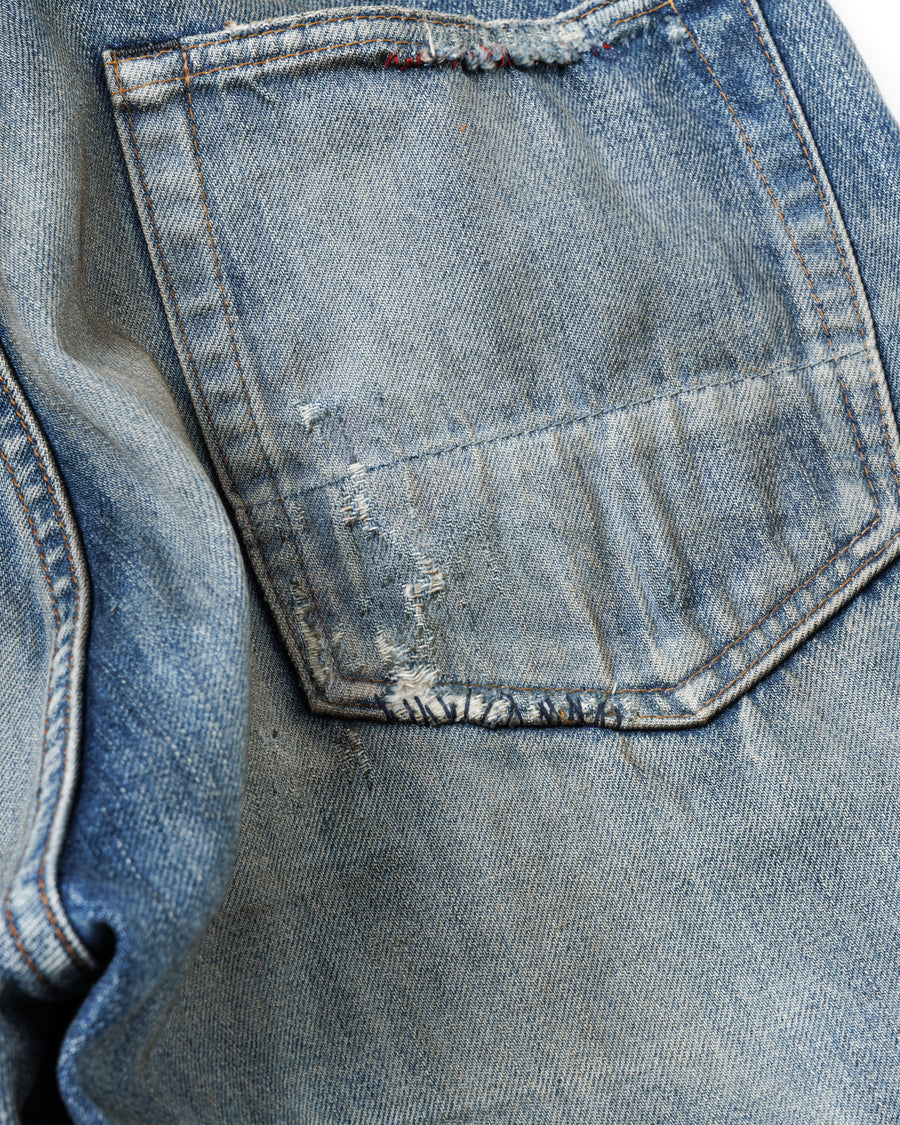 1985年のLEVIS 550をベースに再構築した、ワイドテーパードのリメイク5Pデニム。
12.5ozデニムのタテ糸には中白のインディゴロープ染色糸を使用し、ムラ感のある豊かな表情を演出。タテ落ちとインディゴの濃淡を活かすことで、ヴィンテージにはない独自の風合いを表現しています。さらに手作業のトーンコントロールと特別なエイジング加工を加えることで奥行きある仕上がりに。オリジナル染料の吹き付けにより、モダンでソリッドな印象も併せ持つ一本です。This remade 5P denim features a wide tapered silhouette inspired by the 1985 LEVIS 550.
The 12.5oz denim uses medium-white indigo rope–dyed warp yarns, giving it a textured, slubby character.
By highlighting vertical fading and vivid indigo variations, it achieves a look distinct from vin