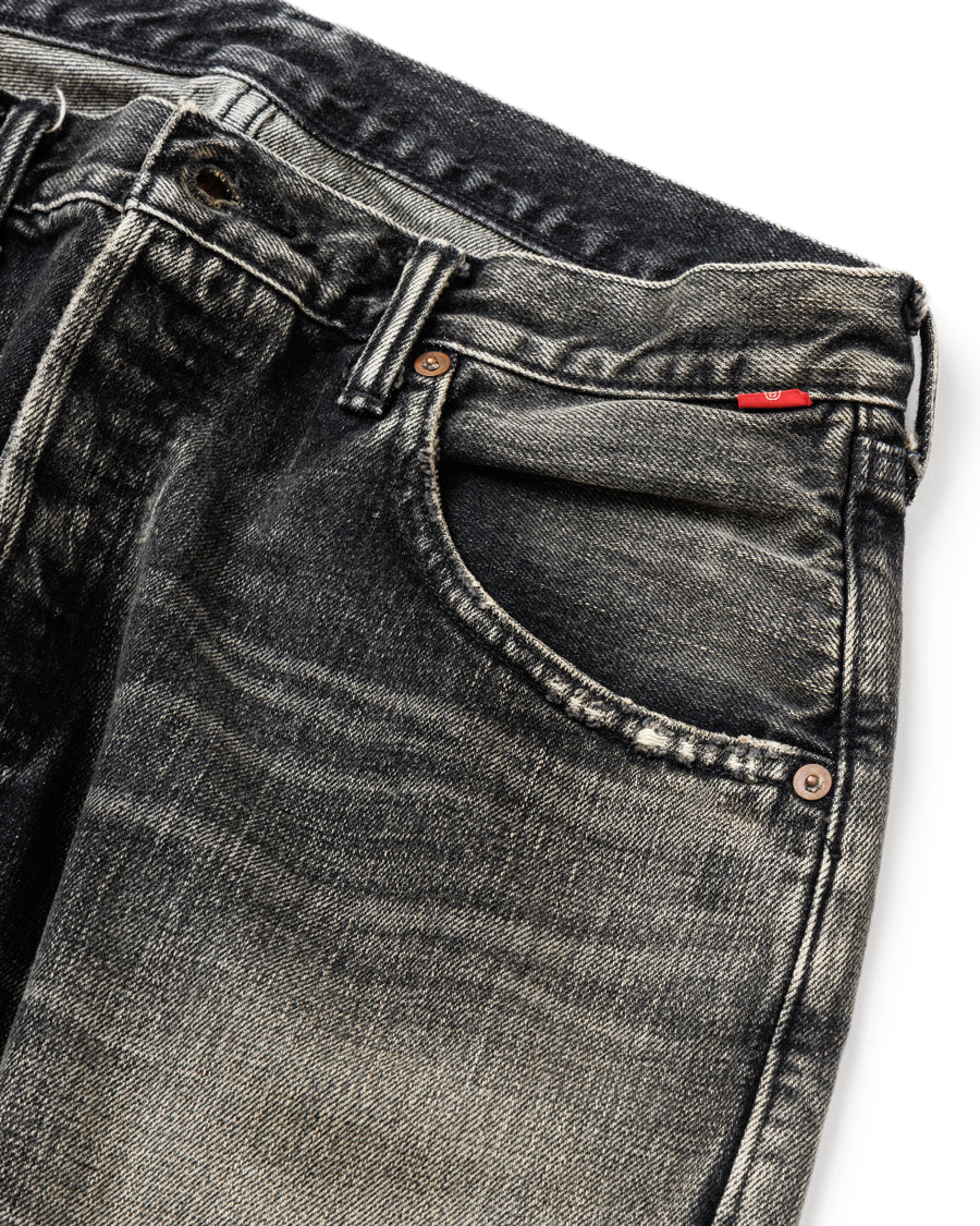 ANACHRONORM定番のレギュラーテーパード5Pパンツをベースに、リメイクで再構築した一本。
腰回りにはゆとりを持たせつつ、裾へ向かってすっきりと収まる美しいテーパードシルエットが特徴です。
タテ糸は硫化ロープ染色を施した芯白仕様で、ブラックからグレーへ自然にフェードする豊かな経年変化が魅力。
ムラ糸が生み出す自然な陰影により、ヴィンテージライクな表情を楽しめます。
さらにタテヨコに硫化ブラックのスラブ糸を使用し、ベーストーンを抑えながらもアタリを際立たせた奥行きのあるコントラストを表現。
リアルなユーズド感を備えた、加工映えする一本に仕上げています。
A reconstructed take on ANACHRONORM’s classic Regular Tapered 5P Pants, refined through its remake design.
The fit offers room around the waist with a clean taper toward the hem, ensuring both comfort and sharp lines.
Warp yarns a