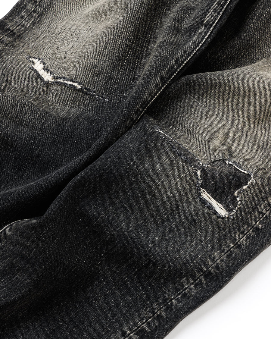 ANACHRONORM定番のレギュラーテーパード5Pパンツをベースに、リメイクで再構築した一本。
腰回りにはゆとりを持たせつつ、裾へ向かってすっきりと収まる美しいテーパードシルエットが特徴です。
タテ糸は硫化ロープ染色を施した芯白仕様で、ブラックからグレーへ自然にフェードする豊かな経年変化が魅力。
ムラ糸が生み出す自然な陰影により、ヴィンテージライクな表情を楽しめます。
さらにタテヨコに硫化ブラックのスラブ糸を使用し、ベーストーンを抑えながらもアタリを際立たせた奥行きのあるコントラストを表現。
リアルなユーズド感を備えた、加工映えする一本に仕上げています。
A reconstructed take on ANACHRONORM’s classic Regular Tapered 5P Pants, refined through its remake design.
The fit offers room around the waist with a clean taper toward the hem, ensuring both comfort and sharp lines.
Warp yarns a