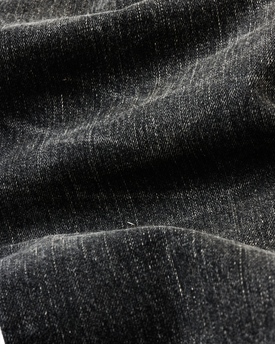 ANACHRONORM定番のレギュラーテーパード5Pパンツをベースに、リメイクで再構築した一本。
腰回りにはゆとりを持たせつつ、裾へ向かってすっきりと収まる美しいテーパードシルエットが特徴です。
タテ糸は硫化ロープ染色を施した芯白仕様で、ブラックからグレーへ自然にフェードする豊かな経年変化が魅力。
ムラ糸が生み出す自然な陰影により、ヴィンテージライクな表情を楽しめます。
さらにタテヨコに硫化ブラックのスラブ糸を使用し、ベーストーンを抑えながらもアタリを際立たせた奥行きのあるコントラストを表現。
リアルなユーズド感を備えた、加工映えする一本に仕上げています。
A reconstructed take on ANACHRONORM’s classic Regular Tapered 5P Pants, refined through its remake design.
The fit offers room around the waist with a clean taper toward the hem, ensuring both comfort and sharp lines.
Warp yarns a