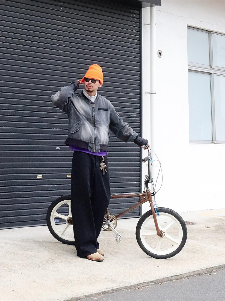 【 商品名：エイジングデュアルデニムMA-1 】

本製品は、ブランドのメイン素材であるデニムを使用し、ディティールを忠実に再現しながらシルエットを整えたブラックカラーのMA-1ジャケットです。中綿は入っていませんが、ライトオンスデニムを採用し、二重縫製によって柔らかく程よい肉感のある着心地に仕上げています。生地にはムラ糸を使用した8ozデニムを採用しており、シャープなムラ形状と粗野な風合いがより一層ヴィンテージ感を引き立てます。さらに加工には、全体にリアルなアタリ感を与えるエイジング加工を施し、深みのある表情を持たせています。