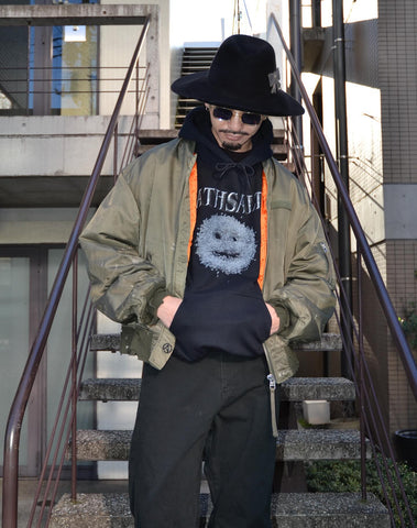 忠実なディテールを保ちながら、シルエットを現代的に整えたMA-1ジャケット。加工によりヴィンテージの風合いを再現した一着です。肉厚でミリタリーらしいツイル生地を使用し、打ち込みの密度や肌触りまでビンテージMA-1に近い仕上がりに。さらに、ダートペイントや特殊吹き付け、ダメージ加工を重ね、洗いをかけて染料を自然に剥がすことで、深みのある表情を生み出しています。カラーはオリーブ。