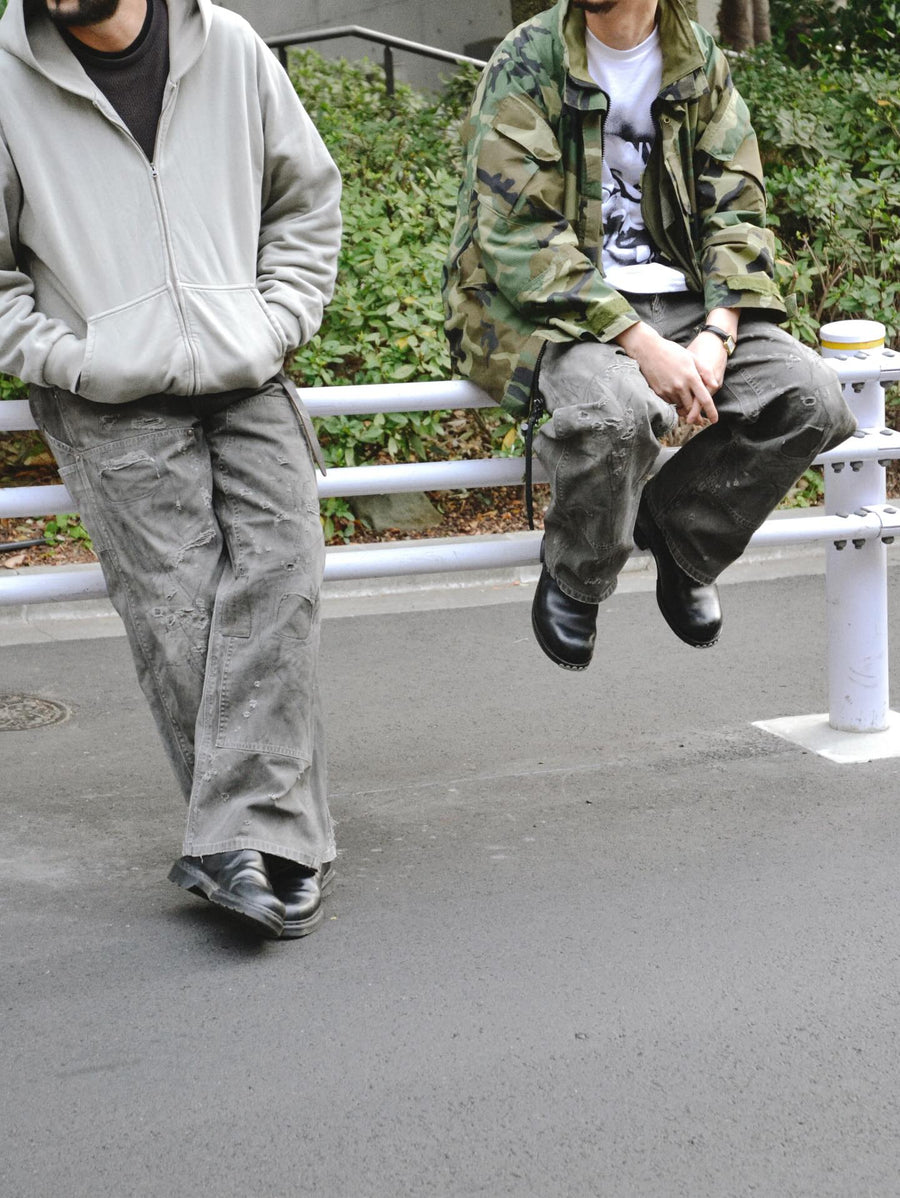 中目黒の「FIFTH GENERAL STORE」とのコラボモデル。同店のダブルニーパンツをベースに、ANACHRONORMが贅沢なリメイクを施しました。高密度ダック地に、独自のG-Brown硫化染めと重層的なバイオ加工、サンフェード、全面の千鳥ステッチ補修を敢行。職人の高度な技術を惜しみなく注ぎ込み、ワークウェアを超越した圧倒的な奥行きとリアリティを追求した究極の一本です。
A collaboration with Nakameguro’s FIFTH GENERAL STORE. Based on their double-knee pants, ANACHRONORM applied luxury distressing, custom G-Brown sulfur dyeing, and meticulous zigzag stitch repairs. It features profound depth and a realistic sun-faded patina, showcasing elite craftsmanship.