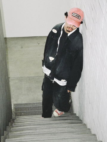 ヴィンテージのワークジャケットを現代的シルエットで再現。柔らかくコシのある20番手ツイルに、環境負荷を抑えた特殊エイジング・サンフェード加工、さらにダメージ加工を施すことで、長年着込んだようなリアルな色落ちと風合いを忠実に表現しました。裏地には高密度なコットンスレーキを採用。鮮やかなブラックのボディに、オリジナルワッペンがアクセントを添える、ヴィンテージ感溢れる一着です。
A modern reimagining of the classic vintage work jacket. Made from soft 20s twill and treated with a special sun-fade and damage process for a realistic, time-worn look. This BLACK jacket features high-density lining and original custom patches, creating a unique, heritage-inspired finish with authentic distressing.