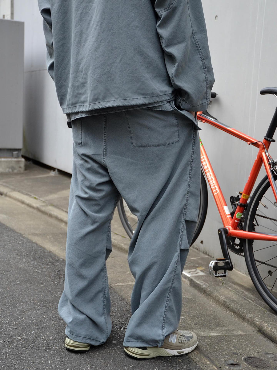 ポリエステル100％ながら、綿のような質感と軽量性を備えた高機能素材を採用。タスラン加工糸によるポリエステルオックスは、シワになりにくく速乾性にも優れています。染色が困難なポリエステルに特殊顔料染めを施すことで、化繊特有の光沢を抑え、ナチュラルで奥行きのある絶妙なフェード感と落ち着いた表情を実現しました。

High-performance polyester oxford with a cotton-like touch, offering quick-dry and wrinkle-resistant benefits. This GRAY BLUE item features a special pigment dye—a rare process for polyester—achieving a sophisticated, faded texture and a matte finish that perfectly balances technical utility with a natural, lived-in aesthetic.