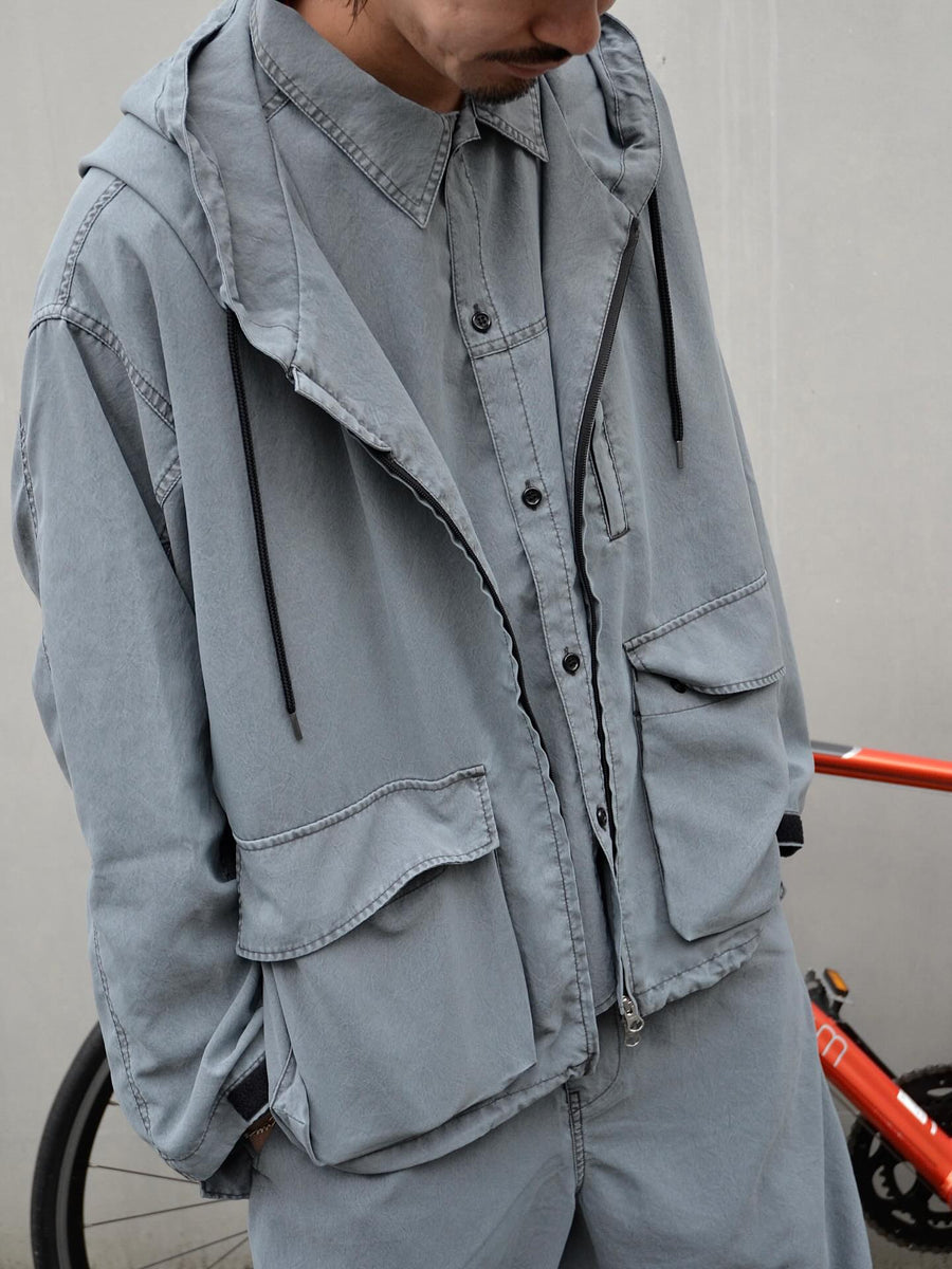 ポリエステル100％でありながら、綿のような質感と軽量性を備えた高機能な一着。タスラン加工糸を使用したポリエステルオックスを採用し、シワになりにくく速乾性に優れたイージーケア性を実現しました。本来染色が困難な素材に特殊顔料染めを施すことで、化繊特有の光沢を抑えた、ナチュラルで奥行きのある絶妙なフェード感を表現しています。

A high-performance piece crafted from polyester oxford, offering a cotton-like touch with lightweight, quick-dry, and wrinkle-resistant properties. This GRAY BLUE item features a special pigment dye—a rare process for polyester—achieving a sophisticated, faded texture and a matte finish that defies its synthetic origins.