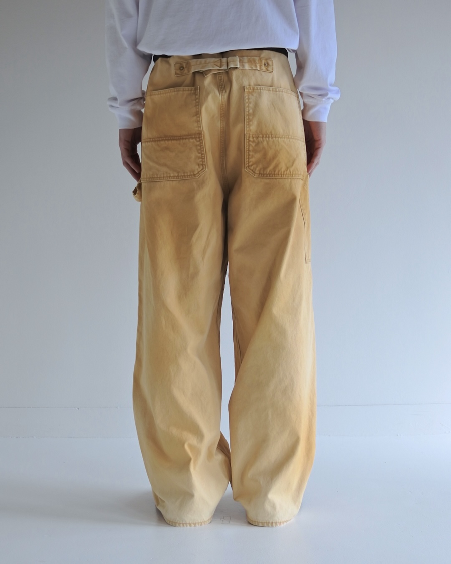 【 商品名：ダブルニーダックペインターパンツ 】

本製品は、レングスをやや長めに設定したイエローカラーのペインターパンツです。ウエスト部分にはナイロンオックス生地で切り替えを施し、ワーク感を抑えたデザインに仕上げています。生地には頒布の中でも最も薄手の11号帆布生地を使用しており、強度・耐久性に優れるだけでなく、着用を重ねるごとにアタリなどの経年変化を楽しめる素材です。また、水や薬品の使用量を抑えつつ生地の凹凸部分のアタリを強調し、同時に自然な脱色感を生み出す特殊エイジング加工を施しています。