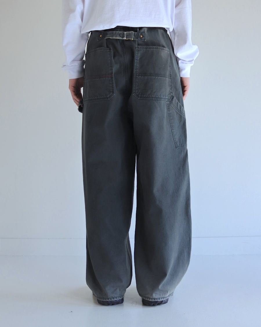 【 商品名：ダブルニーダックペインターパンツ 】

本製品は、レングスをやや長めに設定したブラックカラーのペインターパンツです。ウエスト部分にはナイロンオックス生地で切り替えを施し、ワーク感を抑えた上品なデザインに仕上げています。生地には頒布の中でも最も薄手の11号帆布生地を採用しており、強度・耐久性に優れるとともに、着用を重ねるごとにアタリなどの経年変化を楽しめる素材です。また、水や薬品の使用量を抑えながら生地の凹凸部分のアタリを強調し、同時に自然な脱色感を加える特殊エイジング加工を施しています。