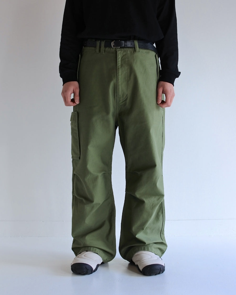 フラップポケットや膝のタック、裾のドローコードなど、ミリタリーディテールを随所に取り入れた1本。通常は内側に配置されるポケットをあえて外側に設けたカーゴポケットが印象的です。ムラ糸で織り上げたバックサテン生地は、独特のハリとコシを持ち、深みのあるオリーブカラーが魅力です。