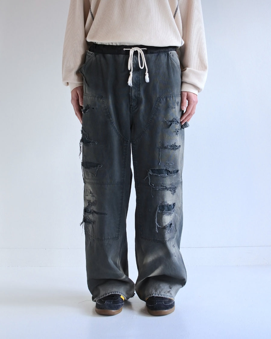 【 商品名：リメイクダブルニーダックペインターパンツ 】

本製品は、レングスをやや長めに設定したブラックカラーのペインターパンツです。ウエスト部分にはナイロンオックス生地で切り替えを施し、ワーク感を抑えつつバランスの良いデザインに仕上げています。生地には頒布の中でも最も薄手の11号帆布生地を使用しており、強度・耐久性に優れるだけでなく、着用を重ねるごとにアタリなどの経年変化を楽しめる素材です。また、水や薬品の使用量を抑えながら生地の凹凸部分のアタリを強調し、同時に自然な脱色感を与える特殊エイジング加工に加え、サンフェードによるダメージ加工も施すことで、より味わい深い表情に仕上げています。