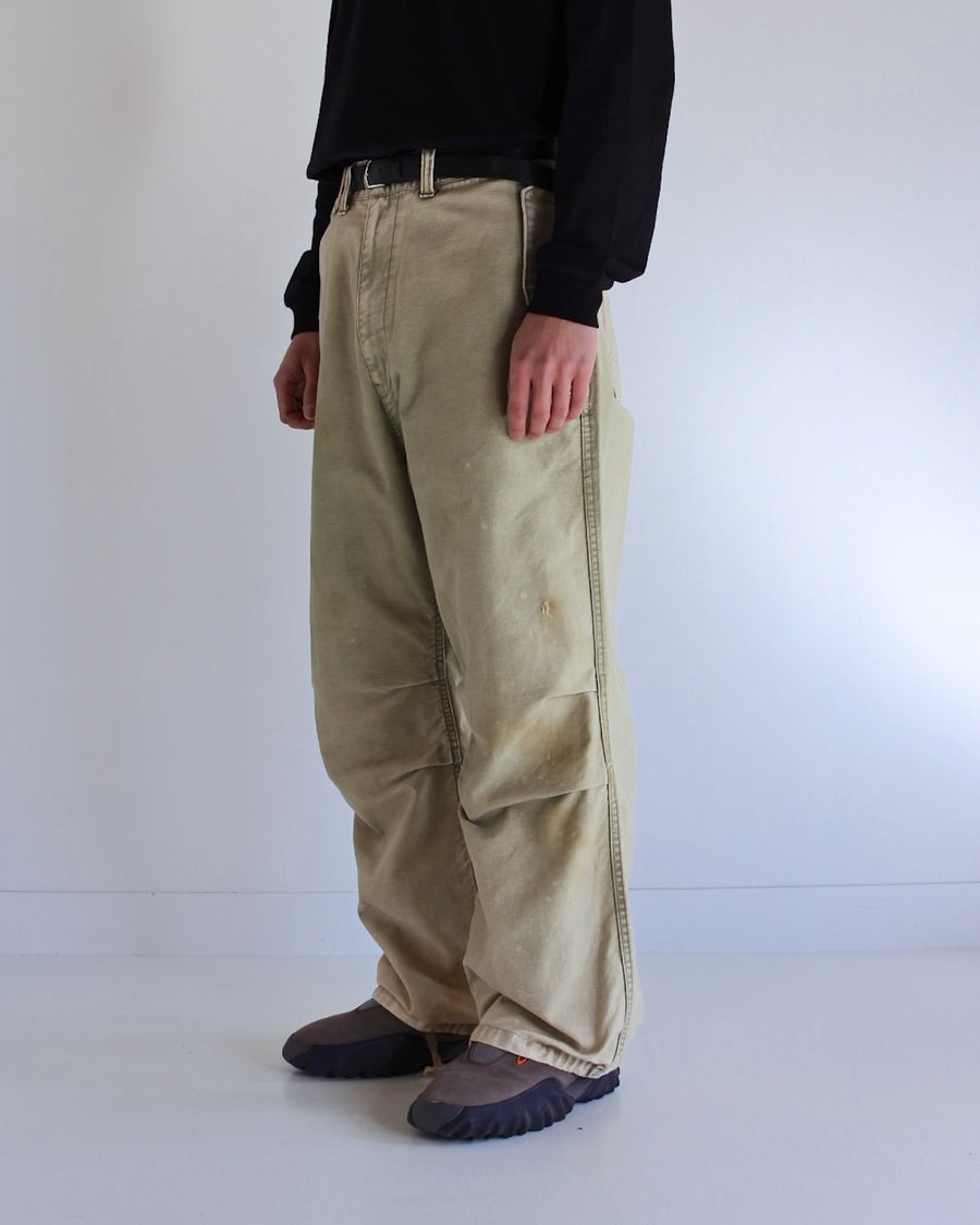 フラップポケットや膝のタック、裾のドローコードなど、ミリタリーのディテールをふんだんに取り入れた一本。内側に配置されることの多いポケットをあえて外側に設けたカーゴポケットが特徴です。ムラ糸で織り上げたバックサテン生地は、ハリとコシのある質感が魅力。さらに、水や薬品の使用を抑えながら生地の凹凸を際立たせる特殊エイジング加工を施し、深みのあるオリーブカラーに仕上げています。