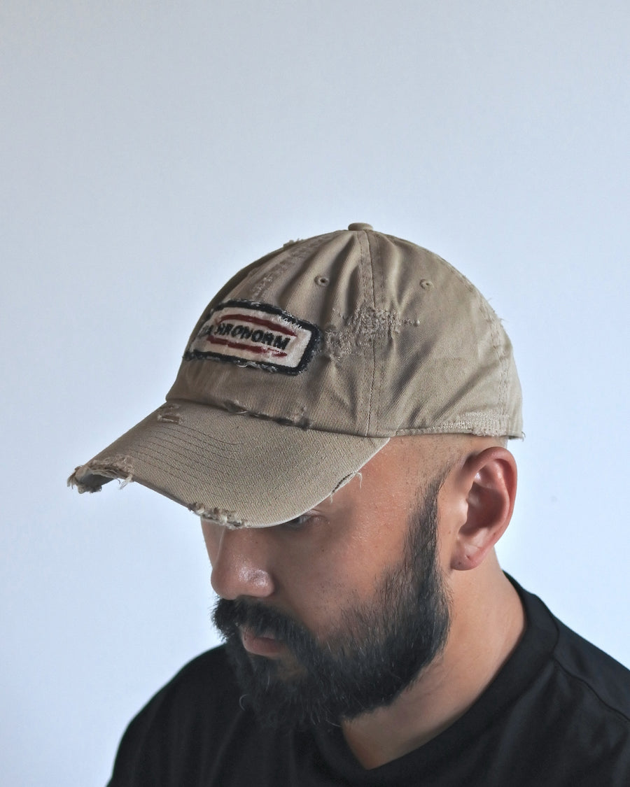 ダメージ加工とステッチ補強で、長年使い込まれた風合いを表現したキャップ。オリジナルワッペンにも同様の加工を施し、全体の統一感を高めました。素材には先染めのピグメントコットンキャンバスを採用。実用性とヴィンテージな佇まいを兼ね備え、スタイリングにこなれたアクセントを添える一着に仕上げています。

A distressed cap featuring reinforced stitching for a rugged, time-worn look. Both the body and the original patch are meticulously aged for a cohesive vintage aesthetic. Crafted from pre-dyed pigment cotton canvas, this BEIGE piece combines durability with a sophisticated, lived-in feel, perfect for adding character to any outfit.