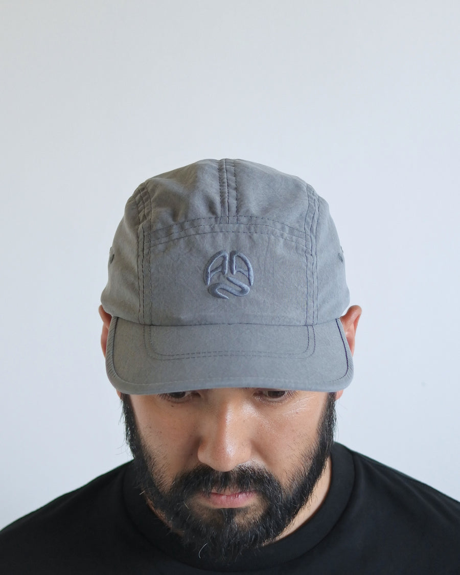 綿のような質感と軽量性を備えた高機能なポリエステルオックスを採用。タスラン加工糸により、シワになりにくく速乾性に優れたイージーケア性を実現しました。染色が困難なポリエステルに特殊顔料染めを施すことで、光沢を抑えたナチュラルで奥行きのある表情に。裏地にはサステナブルなリサイクルメッシュを使用し、快適な着用感にもこだわりました。

High-performance polyester oxford with a cotton-like touch, offering quick-dry and wrinkle-resistant benefits. This GRAY BLUE piece features a special pigment dye for a matte, faded texture, defying its synthetic roots. Lined with eco-friendly recycled mesh, it ensures breathability while maintaining a sophisticated, natural aesthetic.