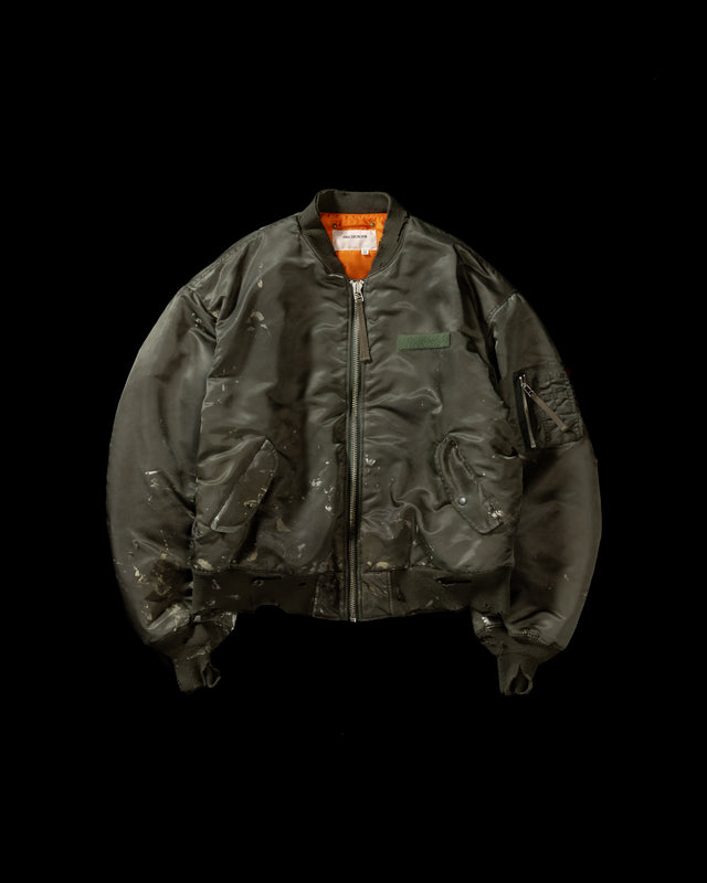 忠実なディテールを保ちながら、シルエットを現代的に整えたMA-1ジャケット。加工によりヴィンテージの風合いを再現した一着です。肉厚でミリタリーらしいツイル生地を使用し、打ち込みの密度や肌触りまでビンテージMA-1に近い仕上がりに。さらに、ダートペイントや特殊吹き付け、ダメージ加工を重ね、洗いをかけて染料を自然に剥がすことで、深みのある表情を生み出しています。カラーはオリーブ。