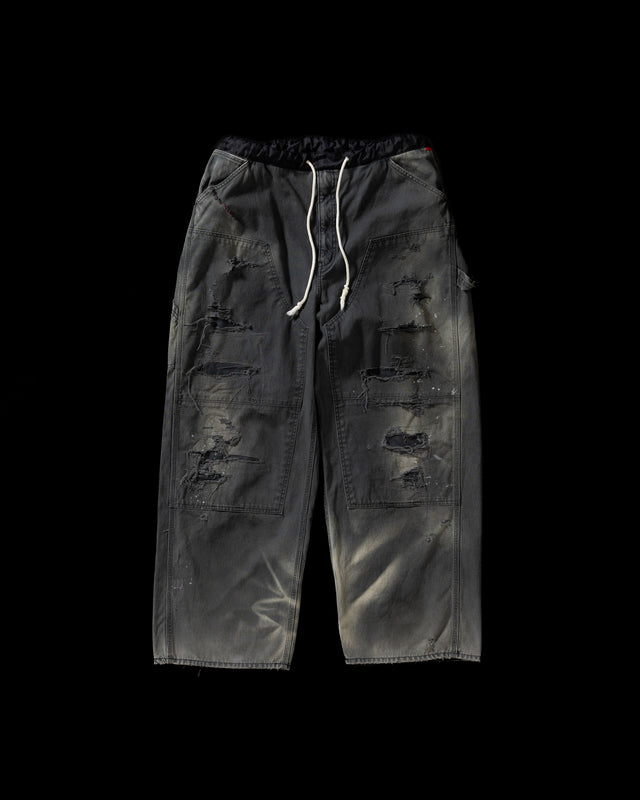 【 商品名：リメイクダブルニーダックペインターパンツ 】

本製品は、レングスをやや長めに設定したブラックカラーのペインターパンツです。ウエスト部分にはナイロンオックス生地で切り替えを施し、ワーク感を抑えつつバランスの良いデザインに仕上げています。生地には頒布の中でも最も薄手の11号帆布生地を使用しており、強度・耐久性に優れるだけでなく、着用を重ねるごとにアタリなどの経年変化を楽しめる素材です。また、水や薬品の使用量を抑えながら生地の凹凸部分のアタリを強調し、同時に自然な脱色感を与える特殊エイジング加工に加え、サンフェードによるダメージ加工も施すことで、より味わい深い表情に仕上げています。